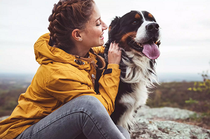 Image of a young adult women sitting on the porch with her dog